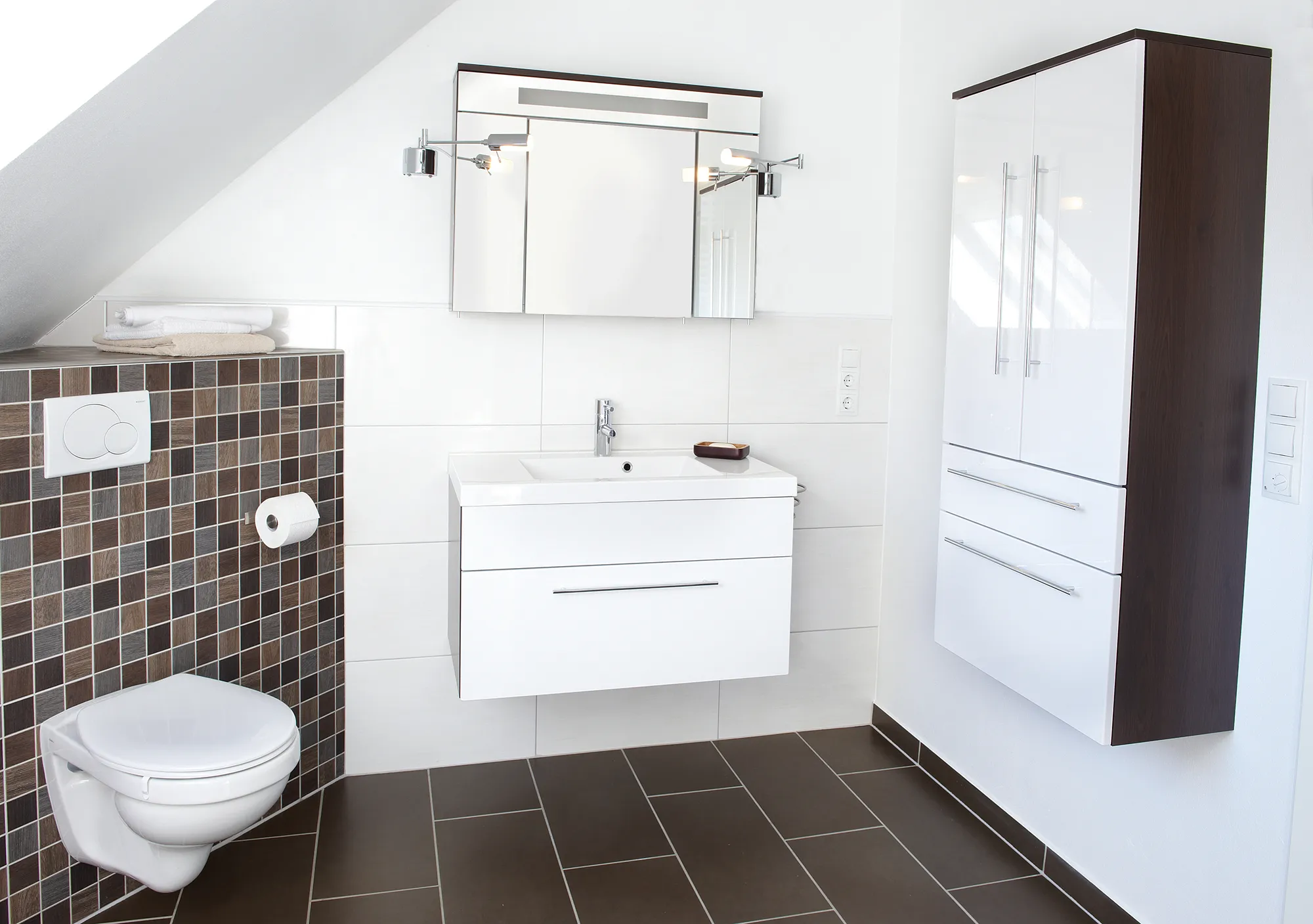 Modernes Badezimmer mit wandhängender Toilette, weißem Waschtisch mit Becken, großem Spiegel und elegantem Schrank. Neutrale Fliesen sorgen für einen klaren, minimalistischen Look.